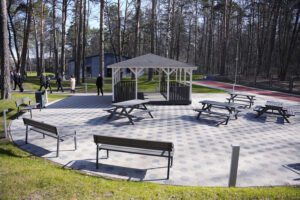 Labiekārtota atpūtas zona ar soliem un galdiem meža teritorijā.