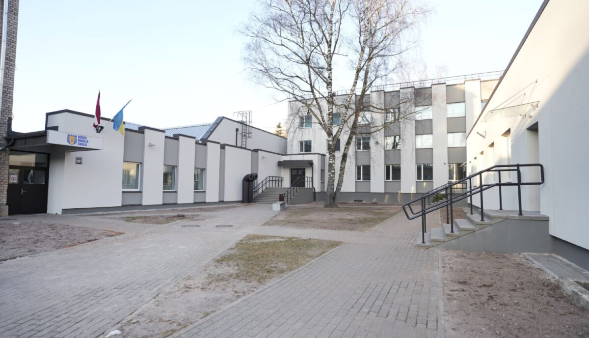 Rīgas hokeja skola - Mūsdienīgs ēku komplekss ar baltām un pelēkām sienām, lieliem logiem, vairākām ieejām ar rampām un kāpnēm. Pie kreisās ieejas redzami divi karogu masti, centrā priekšā atrodas koks. Pagalms bruģēts, ar zālāja joslām gar celiņiem