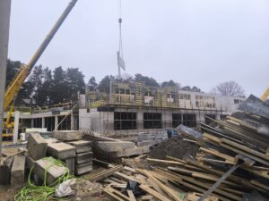 Būvlaukums ar montējamiem dzelzsbetona elementiem, veidņiem un būvmateriāliem ēkas stāvu izbūves procesā