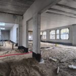 Ēkas iekštelpas ar dzelzsbetona kolonnām, pārsegumiem un smilšu pamatni inženiertīklu un grīdas izbūves sagatavošanas posmā
