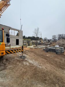 Būvlaukums ar dzelzsbetona ēku, būvmateriāliem un celtņa montāžas darbiem teritorijas attīstības laikā