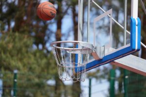 Basketbola bumba lido grozā ar metāla ķēžu tīklu āra sporta laukumā.