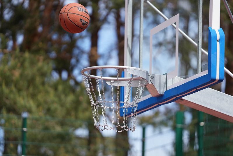 Basketbola bumba lido grozā ar metāla ķēžu tīklu āra sporta laukumā.