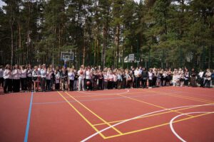 Plašs skats uz āra sporta laukumu, kur sapulcējušies skolēni ar basketbola bumbām pasākuma laikā