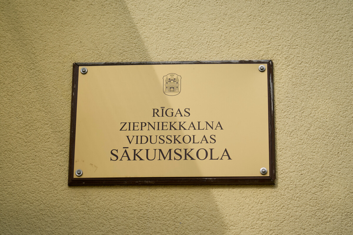Pie ēkas sienas piestiprināta informatīva plāksne ar uzrakstu “Rīgas Ziepniekkalna vidusskolas sākumskola”